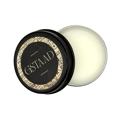 Candle Wise Gstaad solid perfume open black tin with smooth white balm beside lid.