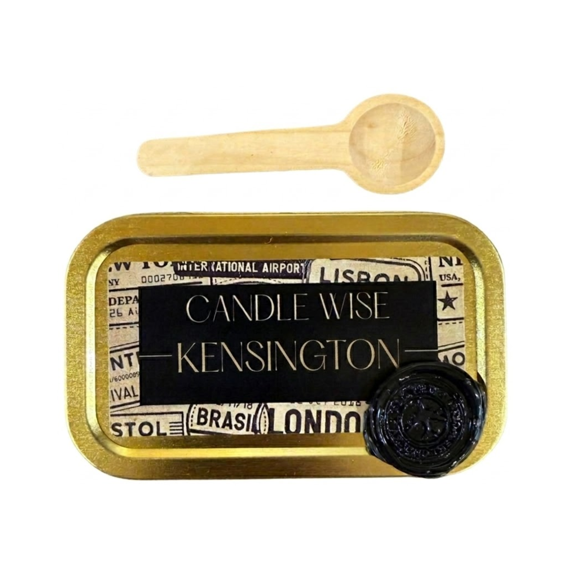 A close up view of the inside of a gold tin containing white scoopable candle wax. The surface of the wax is lightly sprinkled with fine black tea speckles. A wooden scoop rests on the edge of the tin.