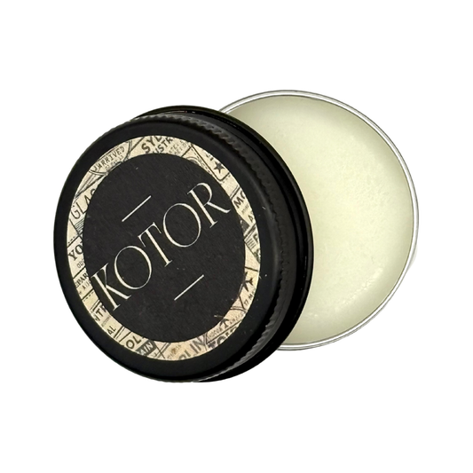 Candle Wise Kotor solid perfume open black tin showing white balm and lid.