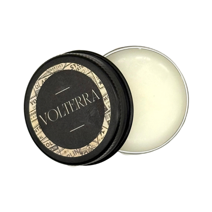 Candle Wise Volterra solid perfume open black tin showing smooth balm with lid beside it.