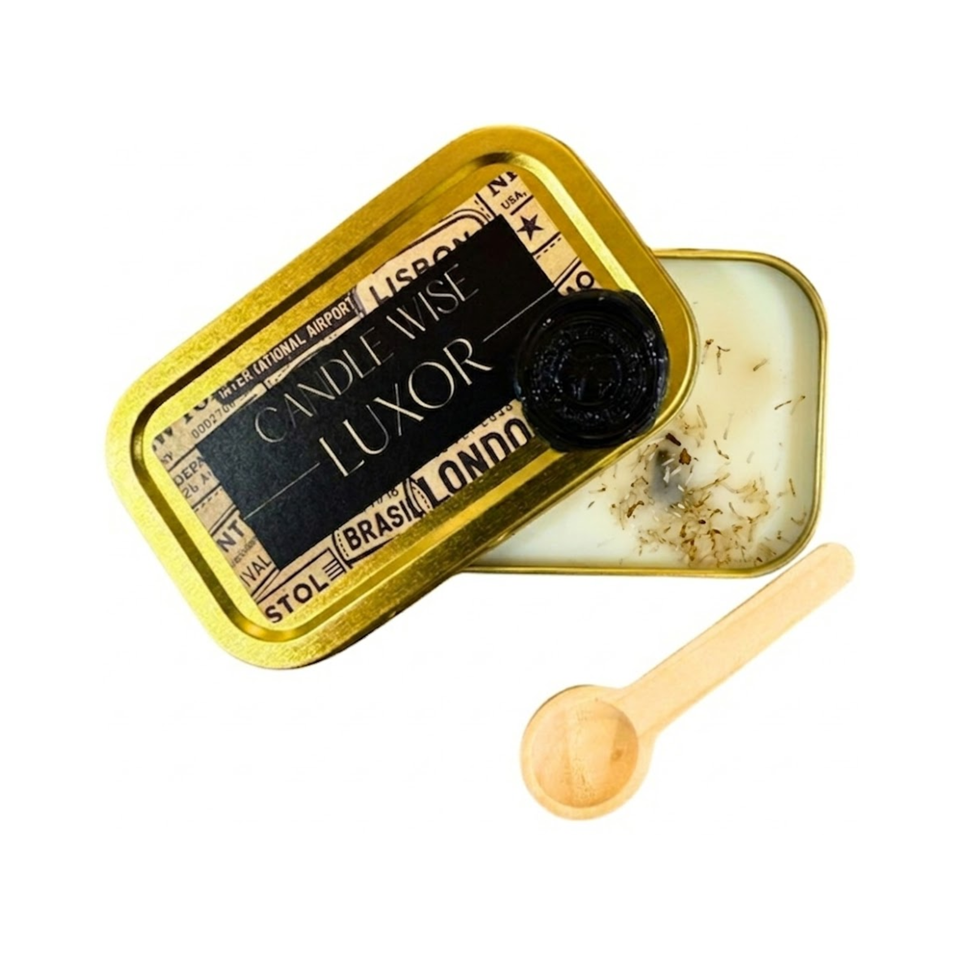 An open gold candle tin with a black "Luxor" label and a black wax seal, showing a cream-coloured candle base with textured organic botanical elements inside.
